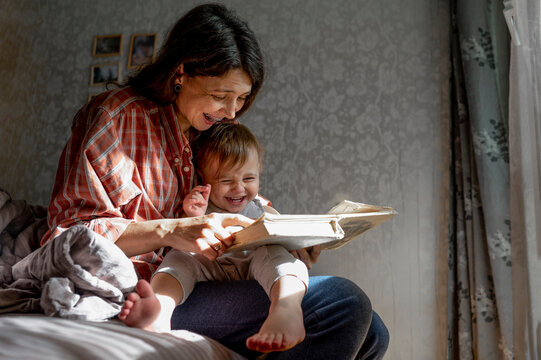 Happy mother with baby reading book at home