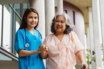 Portrait doctor and female patient smiling. Beautiful female doctor helps senior female patient sick with congenital disease in the hospital during walking exercises regain physical and mental health.