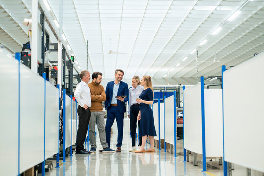 Smiling businessman with colleagues discussing strategy at warehouse