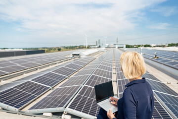 Senior businesswoman with laptop in front of solar panels