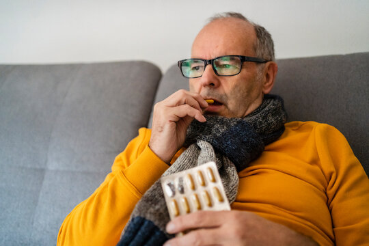 Contemplative man eating capsule holding blister pack at home