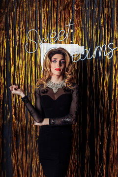 Young drag queen wearing black dress in front of lametta
