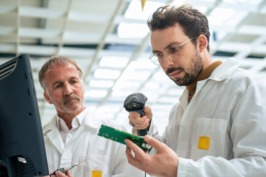 Engineer scanning circuit board with bar code scanner at industry