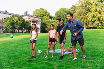 Multiracial family enjoying boules on grass in lawn