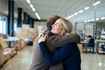 Smiling businesswoman embracing colleague in industry