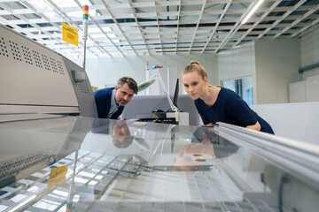 Young businesswoman with businessman examining 3D printing machine
