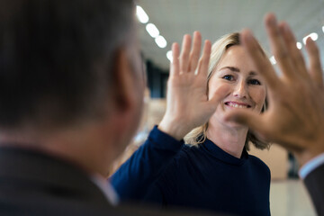 Happy businesswoman giving high-five to colleague
