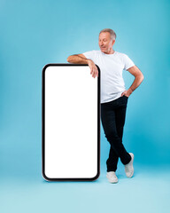 Senior man leaning on big white empty smartphone screen