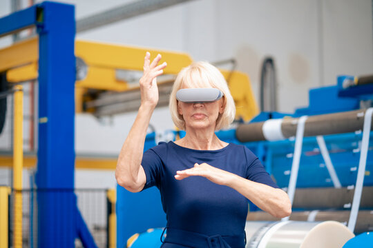 Senior businesswoman with futuristic glasses gesturing in industry