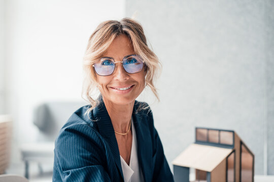 Smiling real estate agent wearing eyeglasses at office