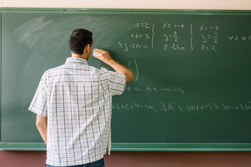 Teacher erasing math formulas on chalkboard