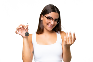 Young caucasian woman holding home keys isolated on green chroma background inviting to come with hand. Happy that you came