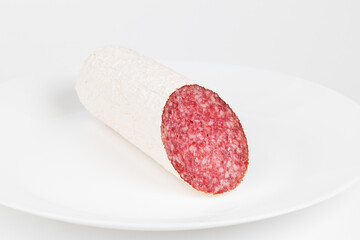 Salami sausage on a white plate, pork snack.