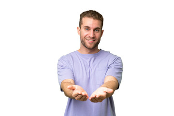 Young handsome caucasian man isolated on green chroma background holding copyspace imaginary on the...