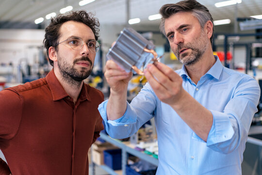 Mature businessman discussing over machine part with colleague in industry