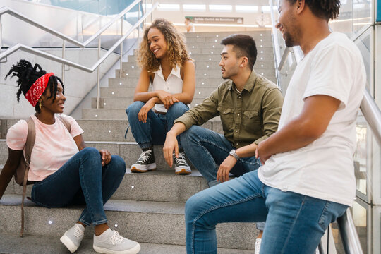 Young Woman With Bandana Talking To Friends On Steps At Railroad Station