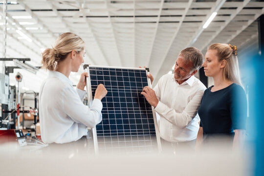 Businesswoman discussing over solar panel with colleagues