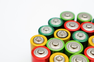 Different colours of batteries on white background. Close up of positive ends batteries, selective...