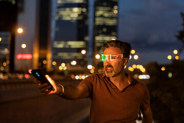 Happy businessman wearing smart glasses at night