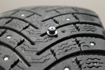 Worn tire tread, winter studded tire - wheel repair service. Renew Lost studs. Old winter studded tire close up. Used snow tire with missing steal studs closeup.