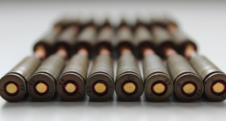 Macro Shot Of A Rows Of Live Ammunition Capsules Laid Out In Order On White Surface
