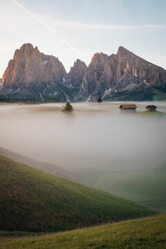 Vertical view of a beautiful sunrise on snowy hills and rocks with mist in South Tyrol