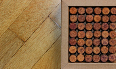 Cardboard box with lined out wine corks on wooden surface on a side of image concept for postcard or wallpaper 