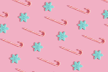Composition made of candy canes and gingerbread snowflake cookies against pink background. Minimal Christmas pattern. Flat lay visual.