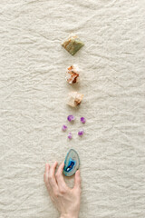 Row of crystals on table, woman hand holding healing minerals agate, quartz, amethyst, onyx,...