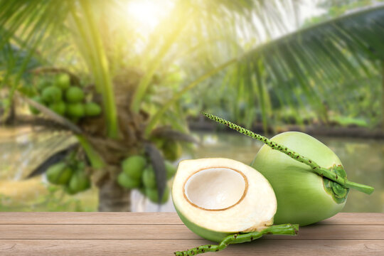 Young Green Coconut With Half Sliced On Wooden Table With Coconut Tree Background.