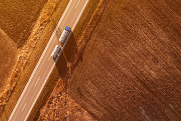 Aerial shot of cistern truck for milk transportation driving along the non-urban landscape in autumn afternoon, drone pov
