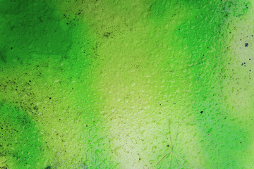 close up of green spray paint or graffiti on the aged white surface of a plastic bench