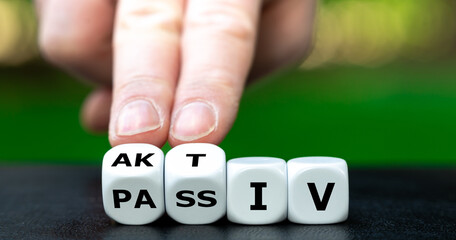 Hand turns dice and changes the German word 'passiv' (passive) to 'aktiv' (active).