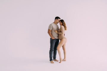 Young couple expecting baby smiling cheerful on white