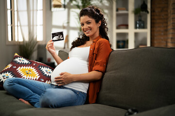 Pregnant woman with ultrasound photo. Beautiful pregnant woman enjoy at home.