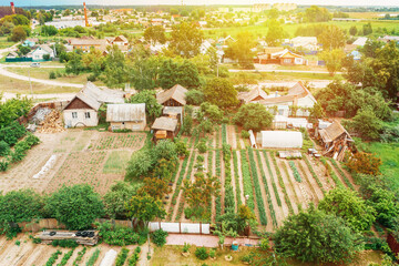 Fototapeta na wymiar Close-up Aerial View On Houses Of Small Village. Houses And Vegetable Gardens. Home Plantations At Summer Day. Village Gardens. Household Plots.