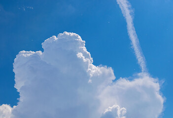 Engine exhaust contrails in the blue cloudy sky.