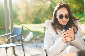 Smiling woman drinking coffee in the outdoors cafe
