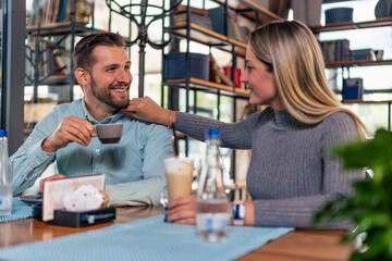 Happy young couple chatting while drinking coffee in a cafe.