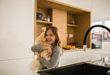 Little girl playing with baby dog in kitchen
Girl hugging dog