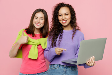 Young two friends IT women in green purple shirts looking camera together hold use work point on...