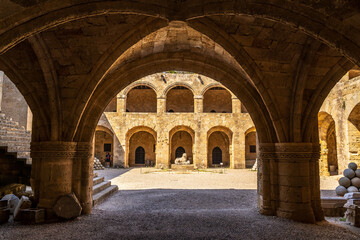 Fototapeta na wymiar View of an ancient building through stone arches in the old town of Rhodes in Greece