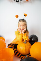 Halloween. A girl in an orange suit leaned her hands on a pumpkin. Postcard with copy space.The...