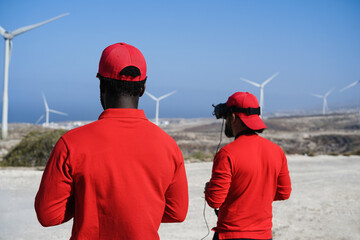 Engineers using virtual reality headset while working at windmill farm - Focus on african man head