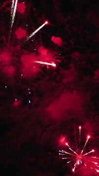 Independence Day. Sparkling red and pink fireworks in the night sky. Abstract background for holiday advertising. Vertical. The concept of a festival and celebration.