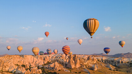 Hot air balloons under rocky landscape of natural formations at sunrise in Cappadocia,   central Turkey.