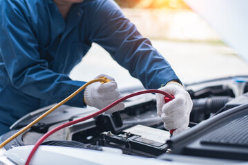 Battery charging. Terminals and hands. auto repair a gas station, hand up close using jumper wires to electrically charge a car battery.