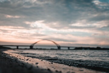 Soft sea waves on a beach with Fehmarn Sound Bridge in the background at sunset