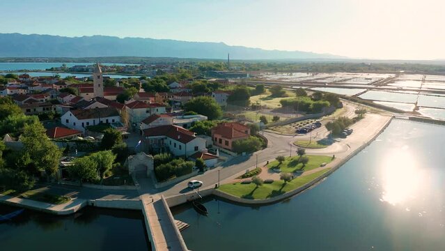 Nin, Croatia - 4K flying sideways by the historic town and small island of Nin with traditional salt still fields and blue Adriatic sea on a sunny summer morning in Dalmatia region of Croatia