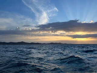 Obraz premium Sunset at the sea, sea horizon, sun rays through the clouds